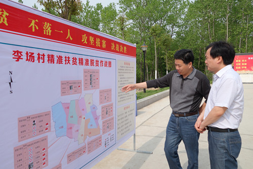 图为蒋场镇镇长（左）向袁溥院长（右）介绍李场村扶贫作战图。.JPG